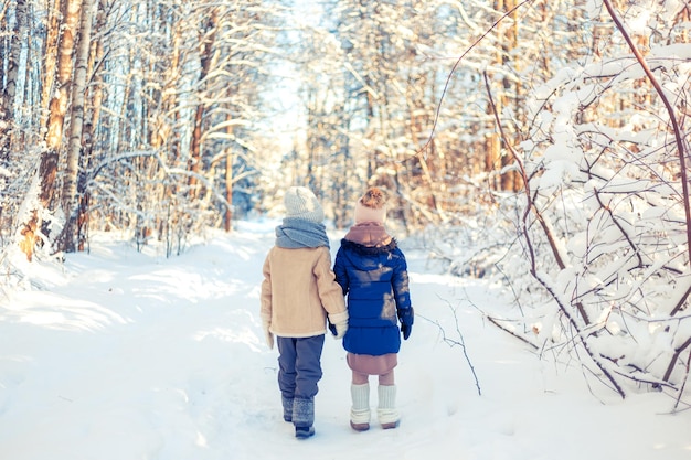 Foto kinder gehen in einem schneebedeckten winterwald spazieren