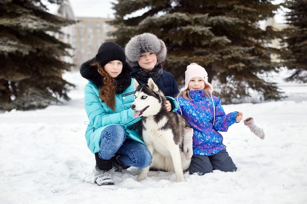 Kinder gehen raus und spielen im Winter mit dem heiseren Hund