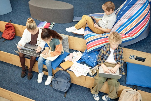 Foto kinder genießen eine pause in der bibliothek und benutzen computer