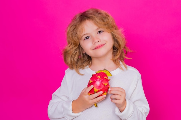 Kinder Gesicht mit Früchten Kid halten Drachenfrucht im Studio Studioportrait von niedlichen Kind mit Drachenfrucht isoliert auf rosa Hintergrund kopieren Raum