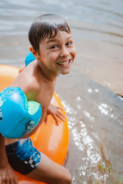 Kinder haben in den Sommerferien Spaß und Spiel im Wasser in einem Teich außerhalb der Stadt im Dorf