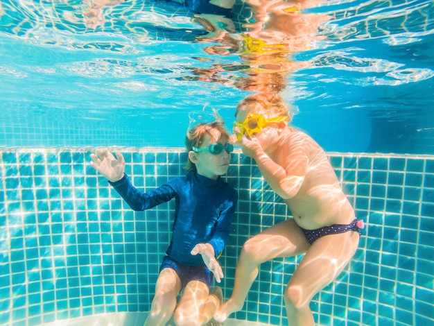 Kinder haben Spaß beim Spielen unter Wasser im Schwimmbad in den Sommerferien