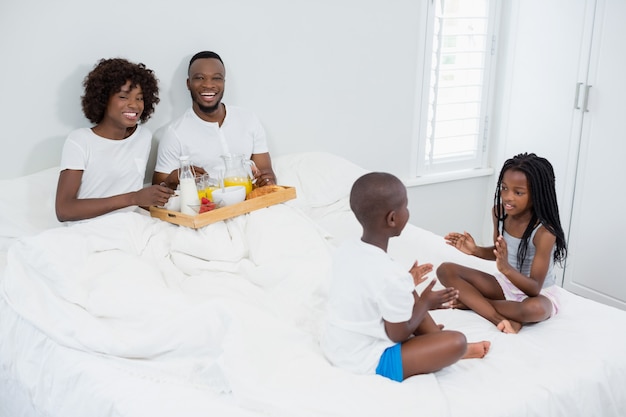 Kinder haben Spaß im Schlafzimmer, während Eltern frühstücken