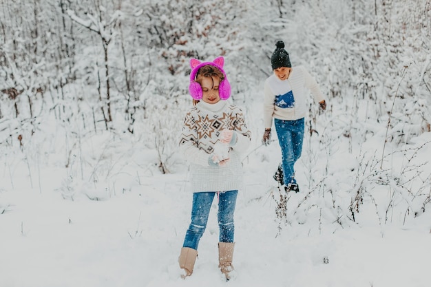 Kinder haben viel Spaß beim Spielen im Schnee. Junge und Mädchen laufen im Winterpark herum. Winterferien