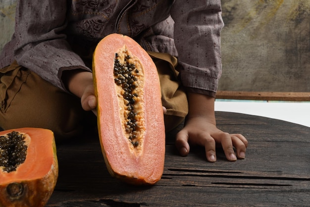 Kinder halten eine Hälfte der Papayafrucht