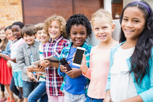 Kinder halten handy und digitales tablet auf schulterrasse