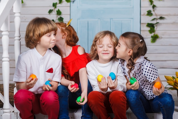 Kinder halten Ostereier. Schöne Kinder sitzen mit Tulpen neben dem Korb und halten Ostereier in den Händen. Lustige Momente