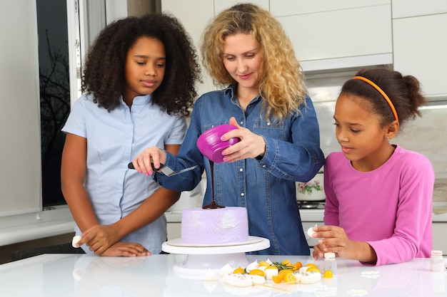 Kinder helfen Mama, den Kuchen zu dekorieren