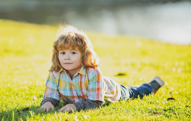 Kinder im Freien Kinder im Park Spring Boy liegt auf dem Rasen Sommerspaziergang Anpassung der Kinder