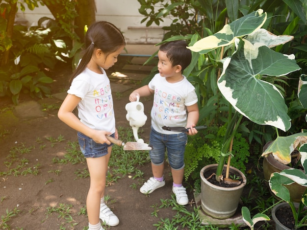 Kinder im Garten gießen die Pflanzen