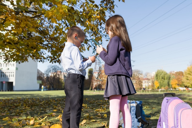 Kinder im Grundschulalter mit Smartphones, Rucksäcken