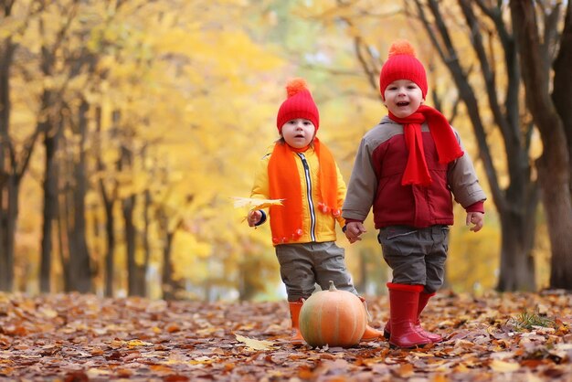 Kinder im Herbstpark mit Kürbis um Herbstblätter