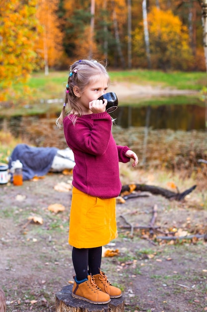 Kinder im Herbstwald auf einem Picknick Tee trinken