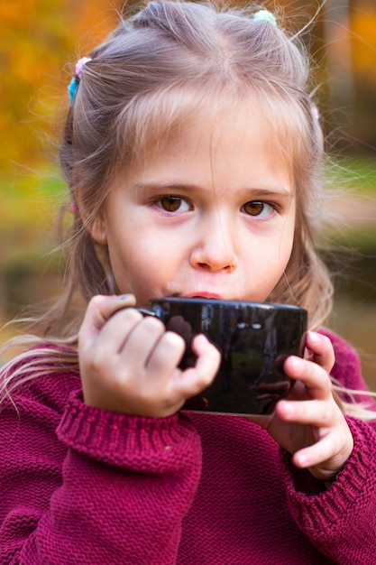 Kinder im Herbstwald auf einem Picknick Tee trinken