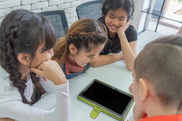 Kinder im Klassenzimmer schauen glücklich auf das Tablet