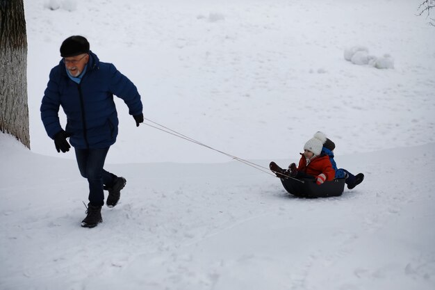 Kinder im Park im Winter. Kinder spielen mit Schnee auf dem Spielplatz. Sie formen Schneemänner und rutschen die Hügel hinab.