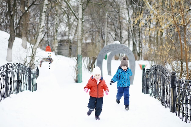 Kinder im Park im Winter. Kinder spielen mit Schnee auf dem Spielplatz. Sie formen Schneemänner und rutschen die Hügel hinab.