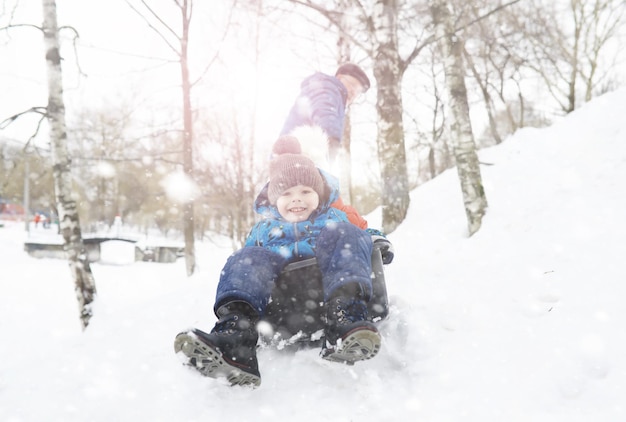 Kinder im Park im Winter. Kinder spielen mit Schnee auf dem Spielplatz. Sie formen Schneemänner und rutschen die Hügel hinab.