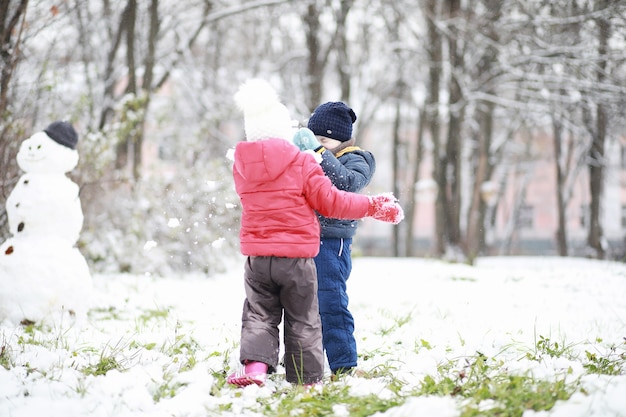 Kinder im Winterpark spielen mit Schnee