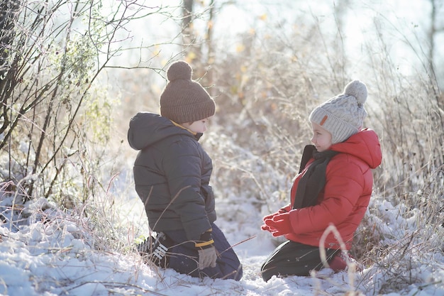 Kinder im Winterpark spielen mit Schnee