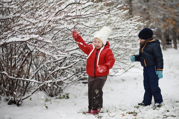 Kinder im Winterpark spielen mit Schnee