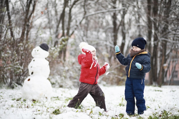 Kinder im Winterpark spielen mit Schnee