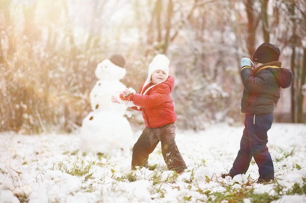 Kinder im Winterpark spielen mit Schnee