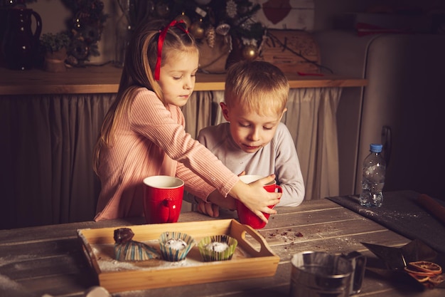 Kinder in der Küche bereiten Kekse zu. Weihnachtsdekorationen, Familientraditionen, Weihnachtsessen, Feiertagsabend.