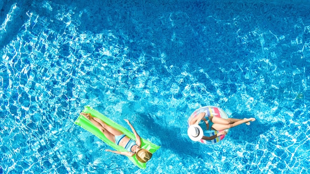 Kinder in der Luftdrohnenansicht des Swimmingpools von oben glückliche Kinder schwimmen auf aufblasbarem Ringkrapfen