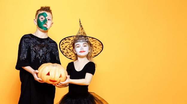 Foto kinder in halloween-kostümen, die mit kürbis spielen