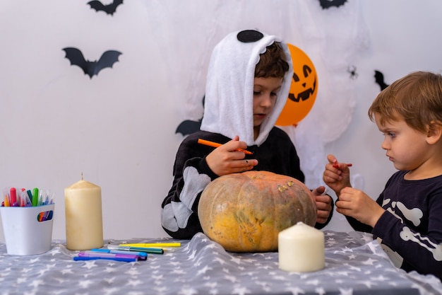 Foto kinder in halloween-kostümen malen kürbisse junge schmücken das haus für den urlaub zu hause