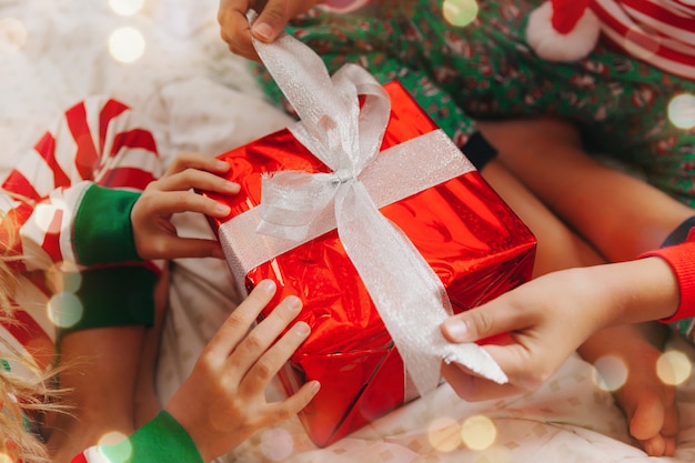 Kinder in Pyjamas und Weihnachtsmützen auf dem Bett mit Geschenken. Weihnachts- und Neujahrskonzept