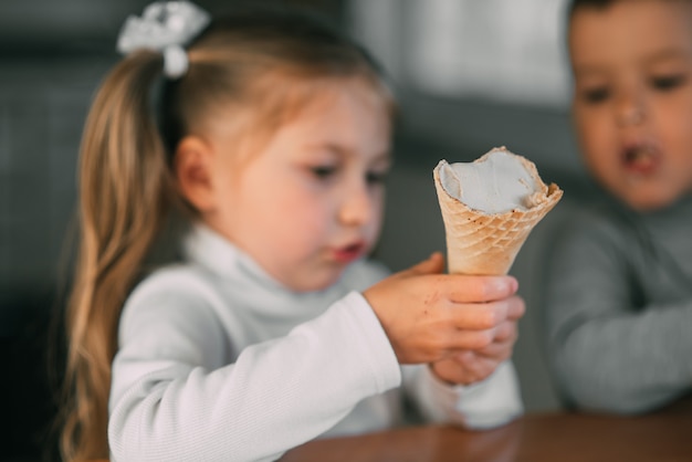 Kinder Jungen und Mädchen essen Eistüte in der Küche ist eine Menge Spaß sehr süß