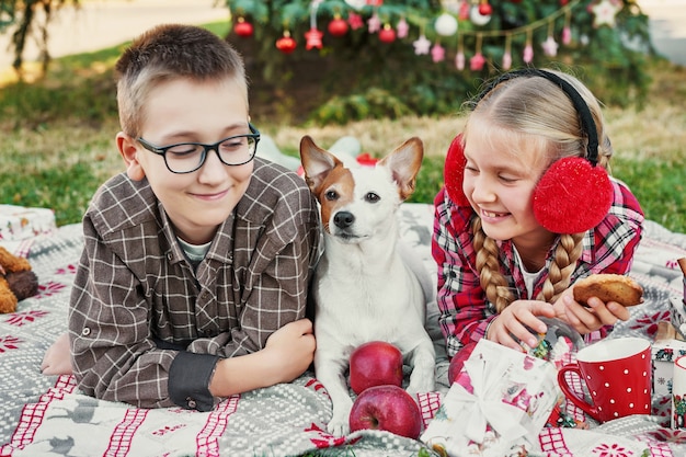Kinder Jungen und Mädchen mit einem Hund Jack Russell Terrier in der Nähe eines Weihnachtsbaumes mit Geschenken,