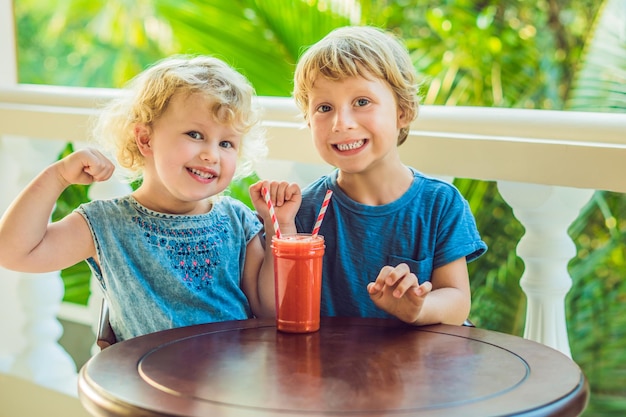 Kinder Jungen und Mädchen trinken Orangen-Smoothie aus Papaya