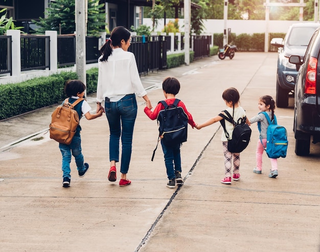 Kinder Kind Sohn Mädchen und Jungen Kindergarten zu Fuß zur Schule gehen Hand in Hand mit Mutter Mutter