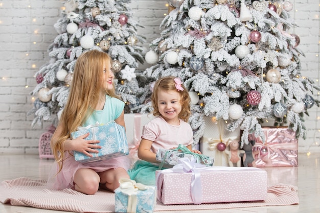 Kinder kleine Mädchen Schwestern mit Geschenken glücklich modisch schön im Weihnachtsinnenraum