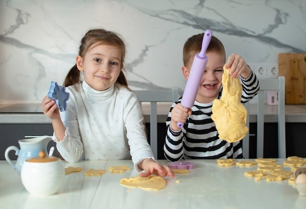 Foto kinder kochen fröhliche kinder backen kekse in der weißen küche kleines mädchen kocht gerne in der küche glückliches kind kocht teig backt kekse in die küche kinder lernen neue dinge