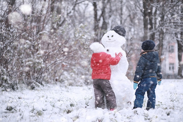 Foto kinder laufen im park mit dem ersten schnee
