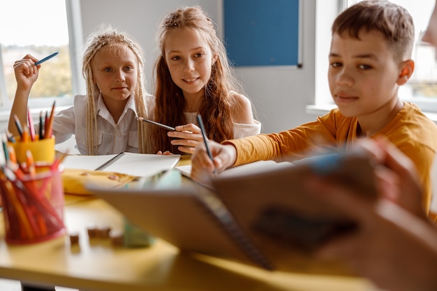 Kinder lernen in der Schule und sitzen am Tisch