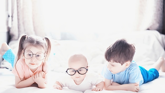 Kinder liegen auf dem Bett neben der neugeborenen kleinen Schwester