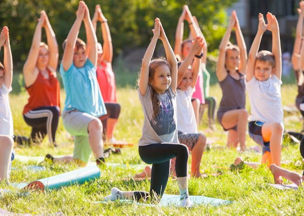 Kinder machen Yoga mit einem Outdoor-Trainer.