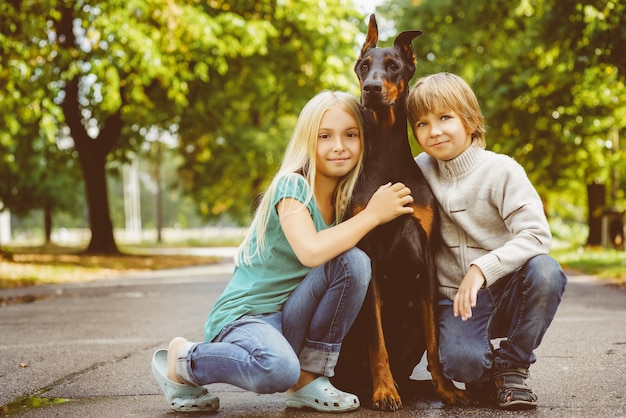 Foto kinder mit dobermann im sommerpark.