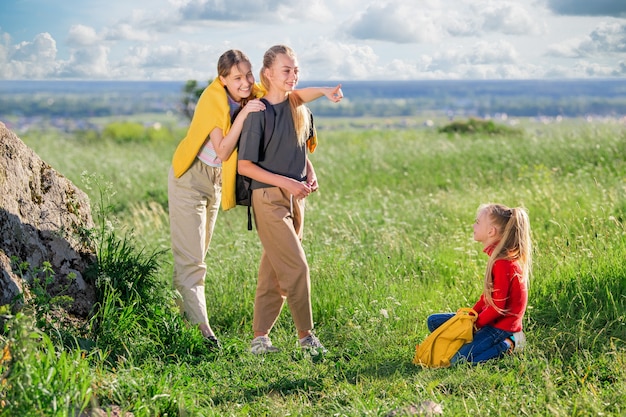 Kinder mit Rucksäcken auf einer Wanderung auf einem Sommerausflug in die Natur. Eine Gruppe von Mädchen im Teenageralter, die Zeit auf einer Wanderung genießen.