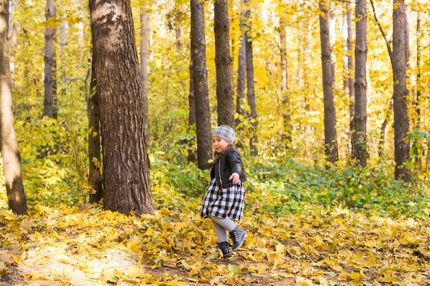 Kinder-, Natur- und Familienkonzept - glückliches kleines Mädchen, das im Herbst auf dem Naturspaziergang im Freien lacht und spielt.