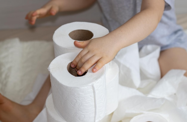 kinder- oder babybeine auf dem bett, das mit weißen toilettenpapierrollen umwickelt ist, braucht während des hygienekonzepts