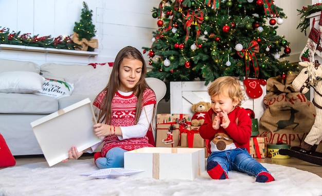 Kinder öffnen Weihnachtsgeschenke unter dem Baum Selektiver Fokus