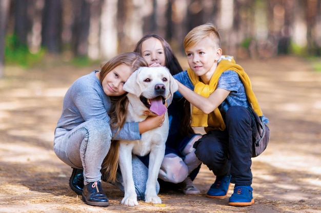 Kinder posieren mit einem weißen Dabrador Gehen Sie mit dem Hund