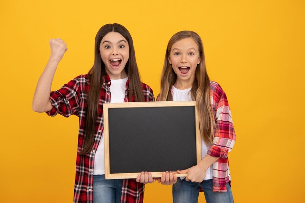 Kinder präsentieren Neuheiten. Kindliche Bildung. Kopieren Sie Platz für die Ankündigung. Förderung des Bildungsangebots. Schule verkaufen. erfolgreiche Mädchen halten Tafel. Kinder Werbung. zurück zur Schule.