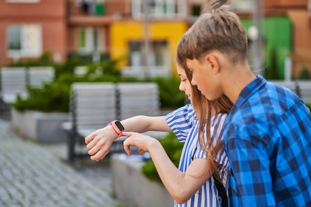 Foto kinder rufen ihre eltern mit rosa smartwatch in der nähe der schule an.